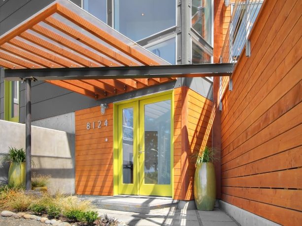a green front door collaborates with orange and gray to create a joyful entryway