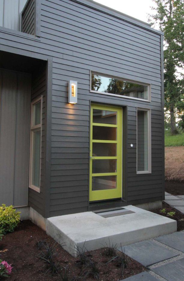 a green front door on a dark gray siding for a cool contemporary entry