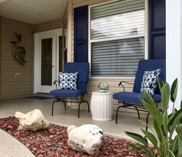 a beach style entrance that lets navy blue shutters meet lenox tan walls and a white garden stool to create really personal space