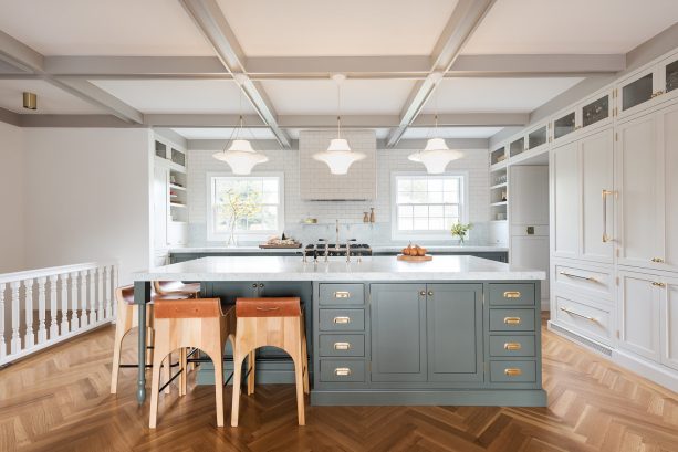 a beautiful set of massive white and gray cabinetry in a two-window georgian kitchen is accentuated by copper dining chairs
