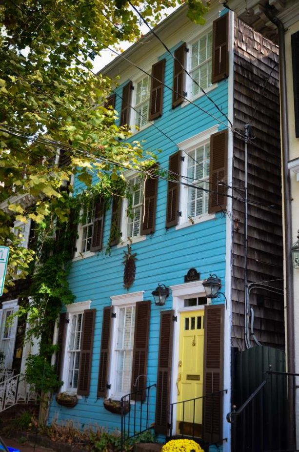 a blue three-story gable roof concrete fiberboard duplex house with a yellow door and brown shutters