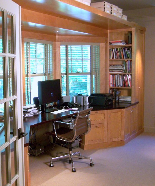 a built-in desk with raw wood color and a dark top and integrated shelves is the best for a bay window