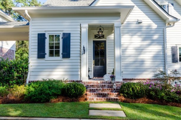 a classic white siding goes really well with navy blue shutters and red brick front entrance stairs