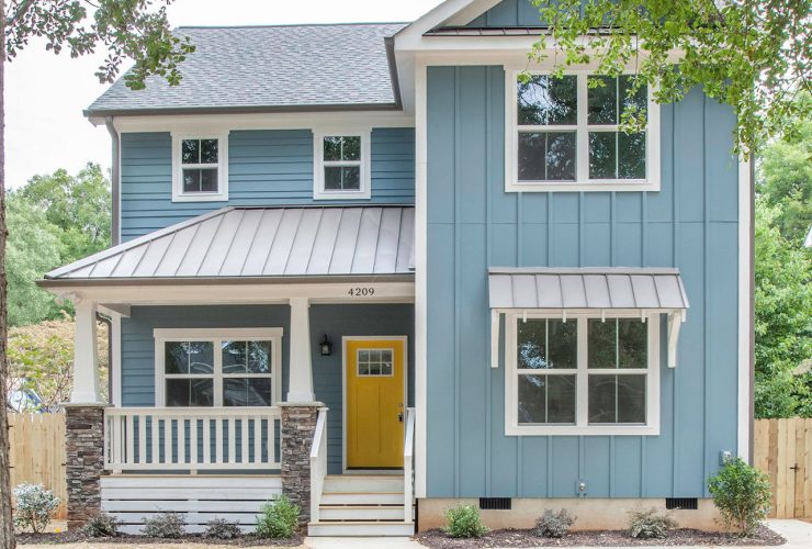 a coastal light blue vinyl exterior house with a yellow door and a mixed material roof