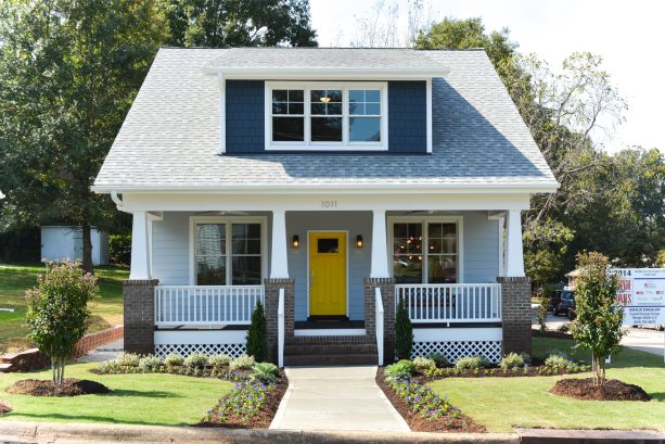 a gable roof house painted in sherwin william's dutch tile blue #0031 and sherwin williams needlepoint navy #0032 with a popping yellow front door