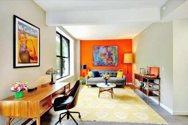 a grey couch in front of a bright orange wall is enough to give a living room an astoundingly gorgeous look