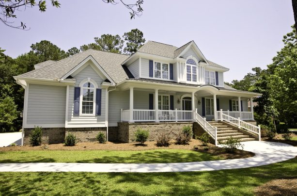 a huge traditional house that blends long navy blue shutters and a wood exterior with a mix of white and light gray