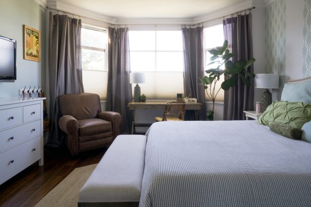 a large bay window with curtains loves the addition of a slim wooden desk with x legs