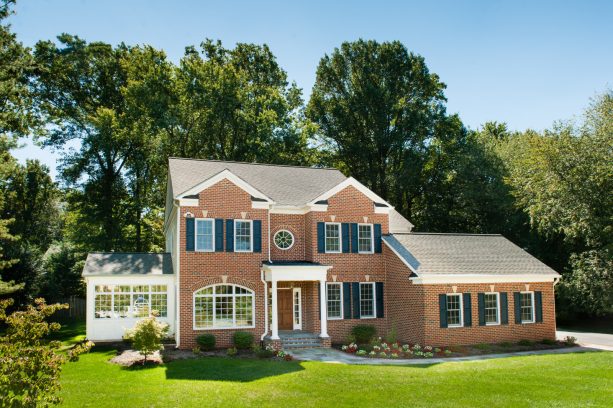 a lovely pairing of red brick walls and navy blue shutters complemented by a gray gable roof