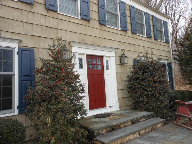 a massive timeless brown exterior with navy blue shutters, white window frames, and a red front door