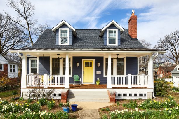 a mega dark blue house with a benjamin moore’s deep ocean hardie board and a bright yellow front door