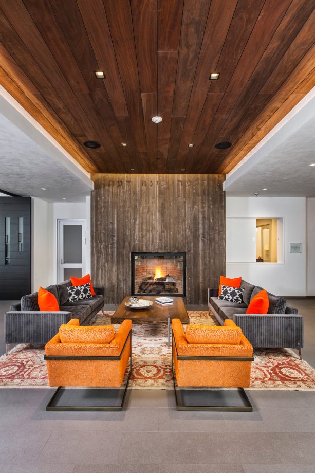 a pair of dark grey sofas and orange armchairs grab all the attention in an open concept living room