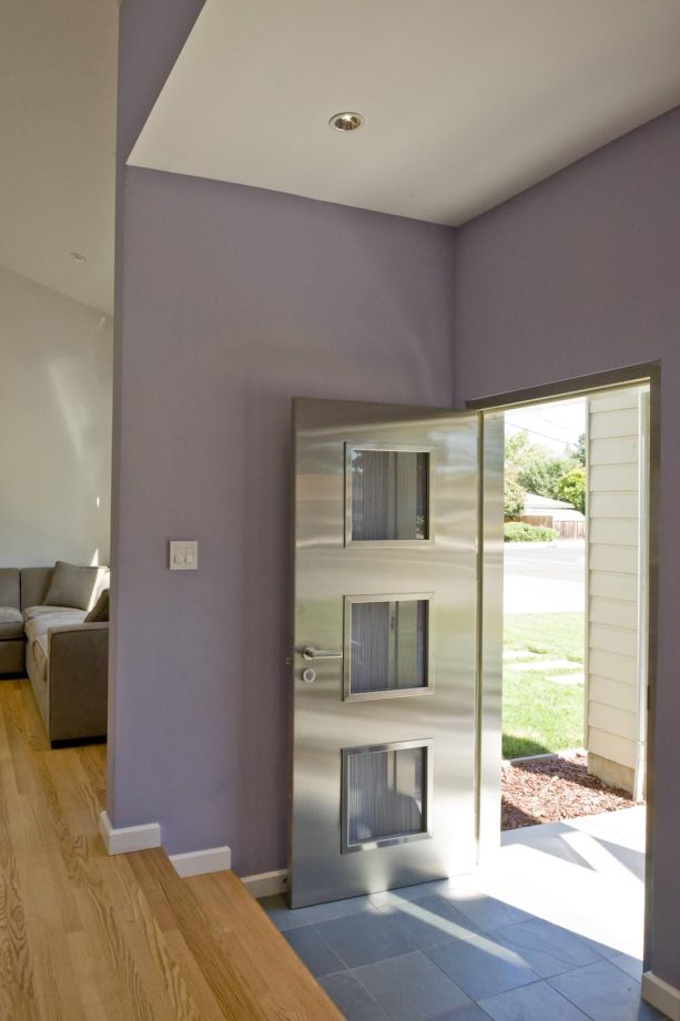 a shiny stainless-steel grey front door and lovely purple walls are a pair that gives a sunken front entryway unparalleled beauty