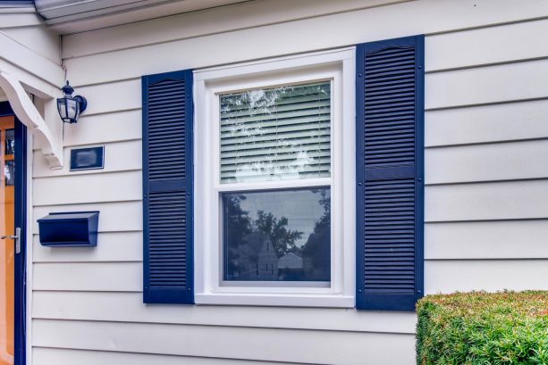 a simple yet stunning combination of a bright white wall and navy blue shutters accompanied by a cute navy blue wall lamp