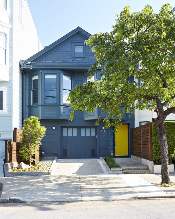 a small victorian wood exterior blue house with a pale yellow front door
