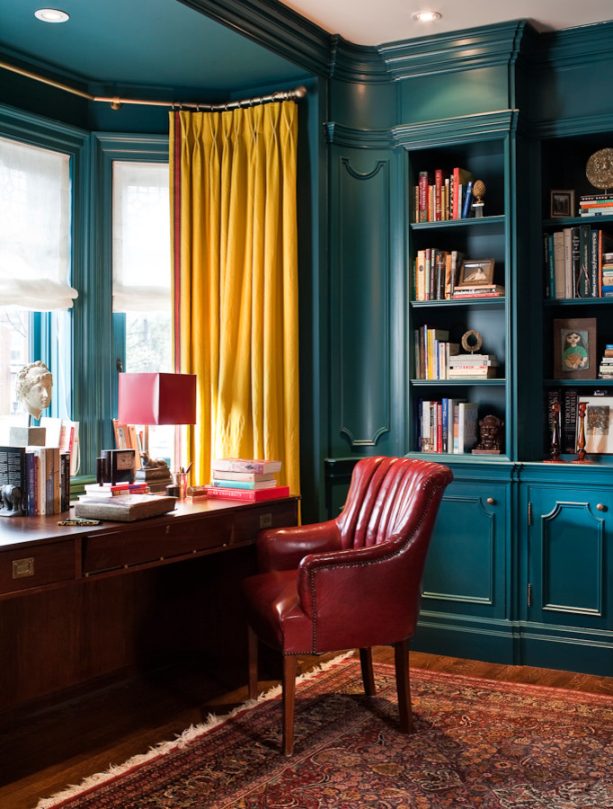 a traditional freestanding brown wooden desk contrasts beautifully against a blue bay window