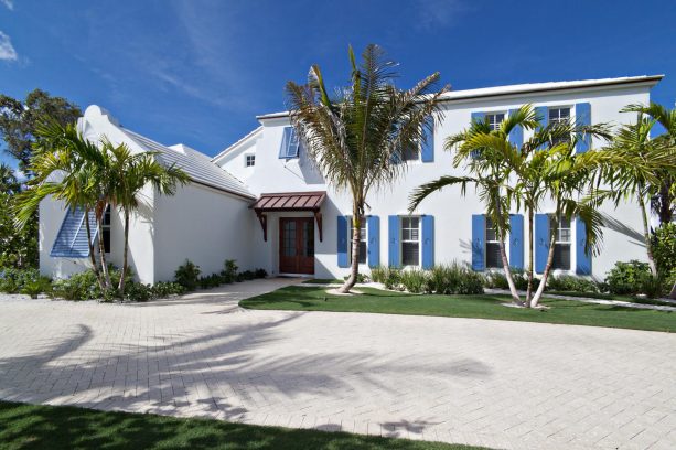 a tropical residence fusing navy blue shutters with white walls and roof accentuated by a brown awning