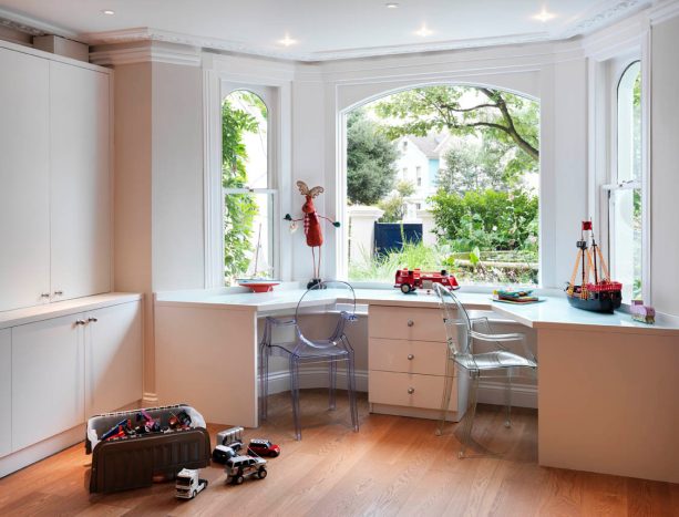 a unique wooden desk with drawers accompanied by clear chairs is the right addition to a bay window with very wide glass in the center