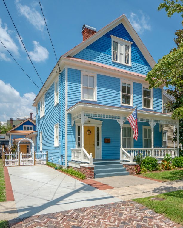 a victorian house was combining bright blue walls and white trims all over with a yellow front door