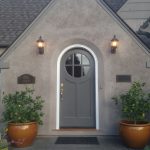 an exterior will look timeless when it has a grey round top front door with a white frame surrounded by walls in a lighter color