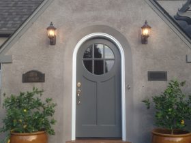 an exterior will look timeless when it has a grey round top front door with a white frame surrounded by walls in a lighter color
