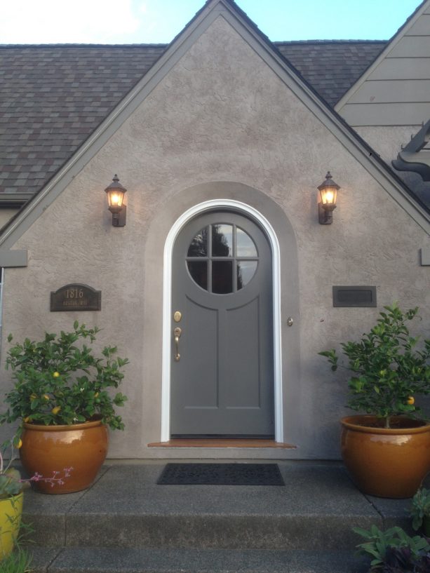 an exterior will look timeless when it has a grey round top front door with a white frame surrounded by walls in a lighter color
