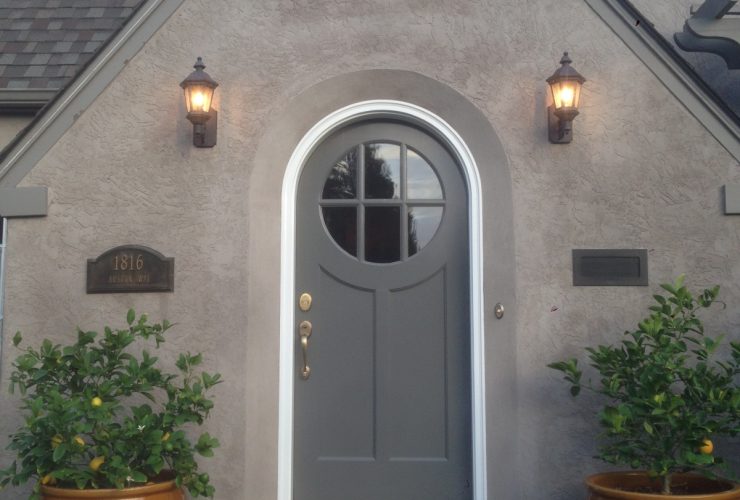 an exterior will look timeless when it has a grey round top front door with a white frame surrounded by walls in a lighter color