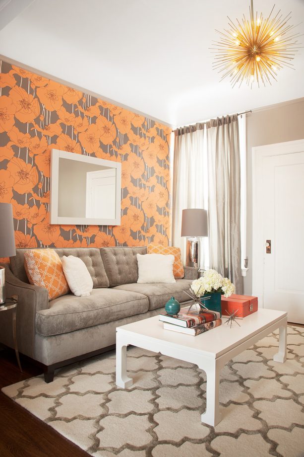 an orange graphic wallpaper and a gray moroccan-style area rug in a small transitional living room