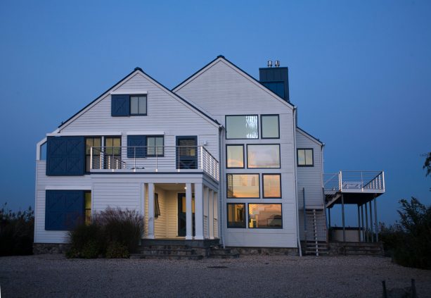 navy blue barn door window shutters and roofs of the same color merge with the tall white wall of a three-story house