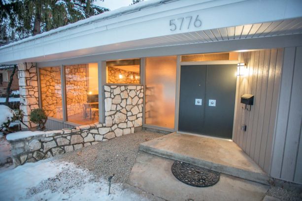 pleasantly welcoming guests to a 1960s mid-century residence is a duty that only double dark grey front doors aided by stones and wood can accomplish
