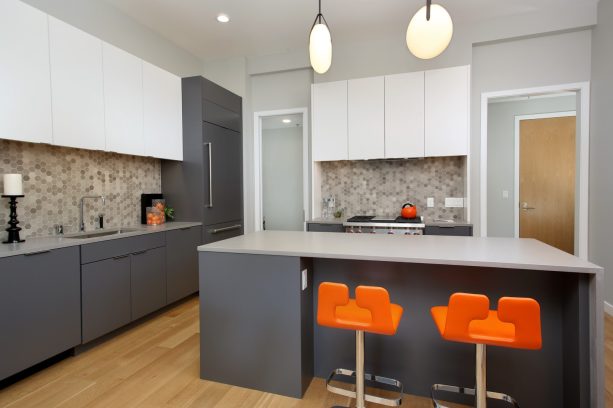 super sleek gray and white cabinets in a contemporary kitchen that has brilliantly popping modern chairs with orange backs