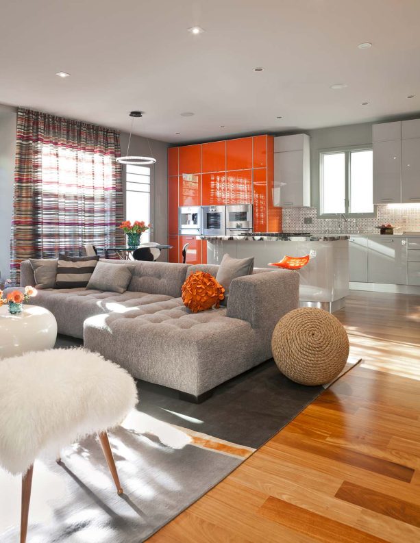 the addition of orange flat-panel cabinets to a living room with a grey ceiling and walls makes the space look heavenly