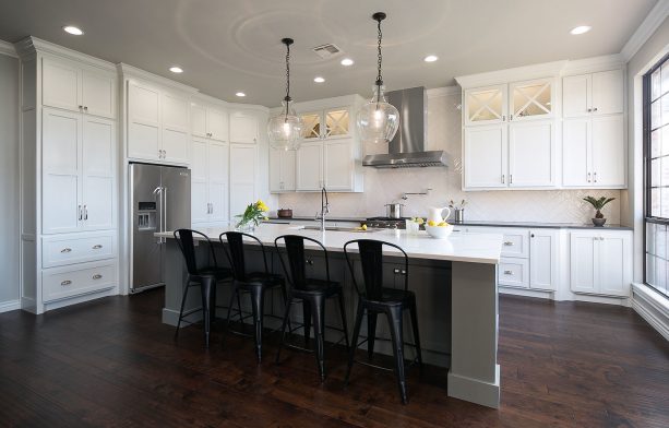 the combo of white cabinets in varying sizes and a gray island cabinet suits a kitchen with a dark wood floor very well