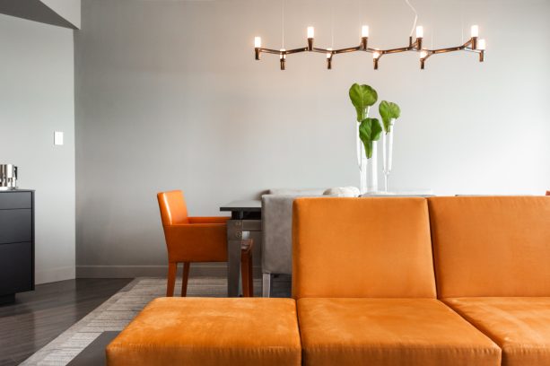 the contrast between an orange platform sofa and light gray walls is so beautiful any living room would embrace it without a second thought