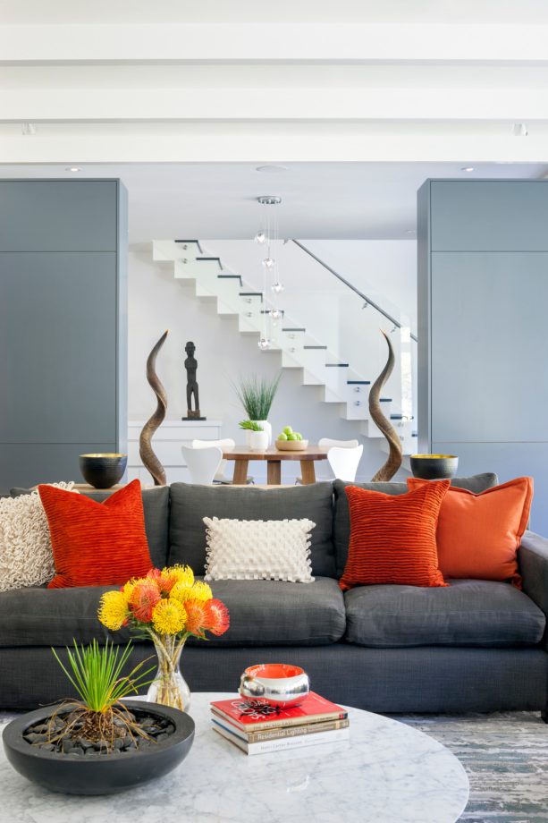 the things that a living room with a grey sofa and walls needs the most are brightly popping orange pillows