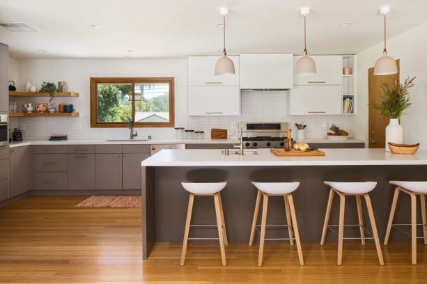 warmth and coziness are guaranteed in a kitchen with white flat-panel wall cabinetry and long gray cabinets below