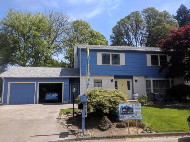 when blue envelopes a mid-sized transitional concrete fiberboard exterior home with a yellow door