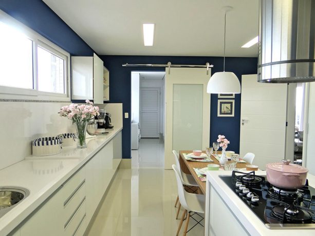 a barn door is a unique addition to a kitchen with navy walls put against white cabinets