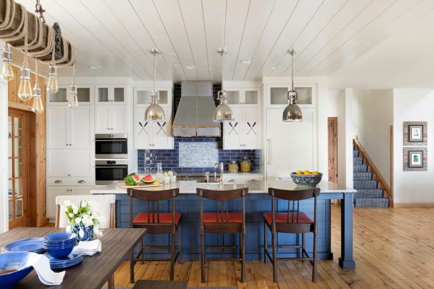 a beach-style kitchen with white cabinets and a big navy island matched by a blue subway tile backsplash