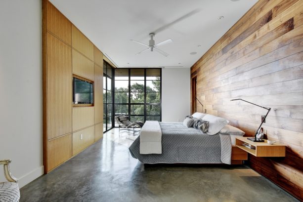 a bedroom with two different types of walls sandwiching a grey concrete floor