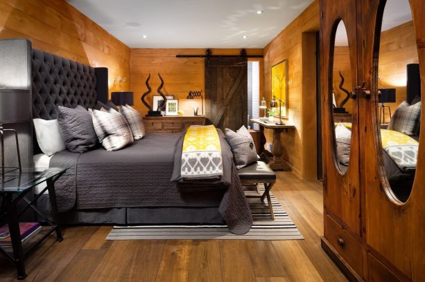 a brown bedroom with a tall grey bed and a barn door