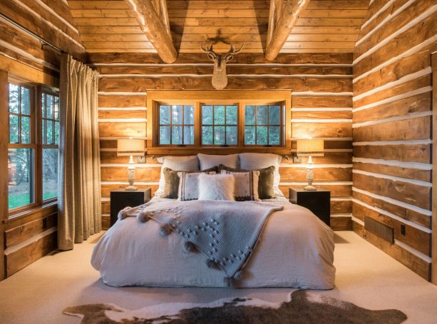 a brown bedroom with log and chinking walls and a grey bed