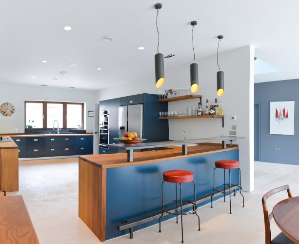 additions of red, brown, black, and yellow beautify a contemporary navy and white kitchen