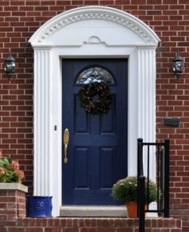 dark blue colonial front door surrounded by brick walls