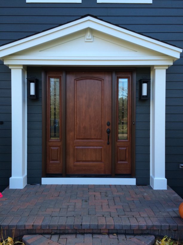 dark tone wood colonial front door surrounded by a white portico