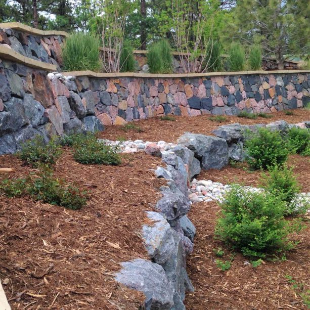 multiple tiers of dark rip rap retaining walls create leveled areas of interest