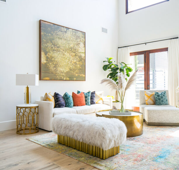 a gold table in the center of a white living room brings beauty into the space