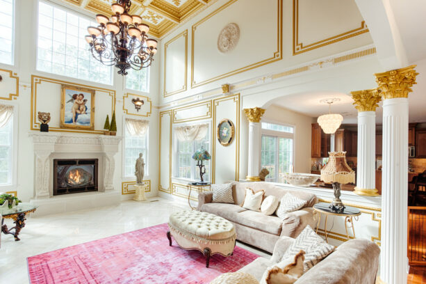 a large timeless traditional living room whose pillars and walls are embellished with gold