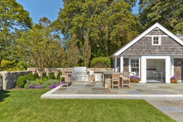 a raised bluestone paver patio with a kitchen is an elegant addition to a pool house