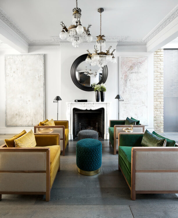 a white living room with gold armchairs in a face-to-face position with dark green chairs with identical designs